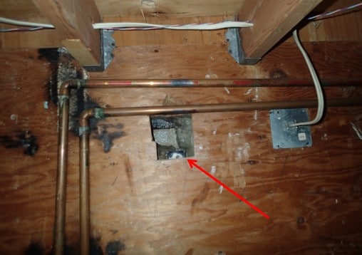 Behind the water heater. Exposed waste line.